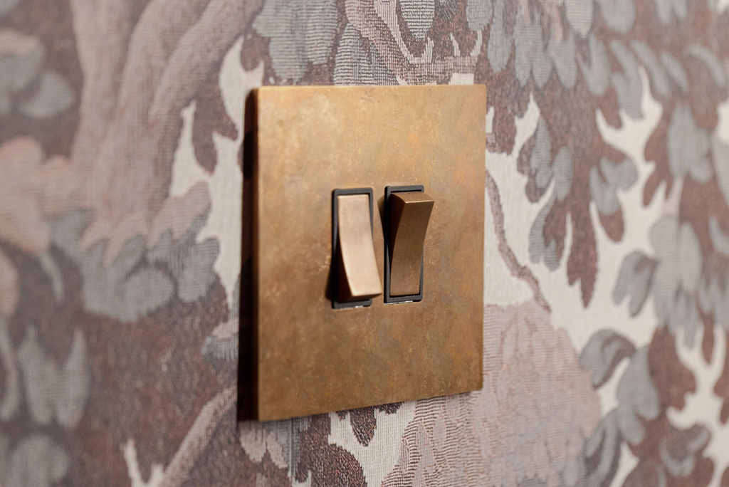 Bronze light switch on a floral wallpaper background